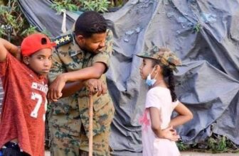 صورة إرشيفية لأطفال سودانيين يتبادلون  الحديث  مع  ضابط في الجيش السوداني